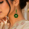 Woman wearing green safety pin earrings with floral pearl design and modern western outfit closeup